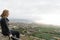 Teenager thinking sitting in fence on a viewpoint of Tenerife north. Blond hair girl relaxed with contemplation in distant in a