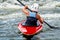 A teenager trains in the art of kayaking. Boat on rough river rapids. The child is skillfully engaged in rafting.