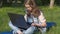 A teenager is typing on a laptop in nature. The girl is sitting on the carpet in the park. A teenage girl on a sunny day with a la