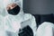  teenager in viral protective suit, black mask and medical gloves looks at the phone and thinks how to stop the coronaviru