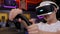 A teenager in VR glasses turns the steering wheel while playing a video game.