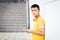 Teenager waiting leaning on wall with yellow t-shirt