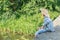 Teenager with wooden rustic fishing rod angling on concrete bridge