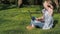 Teenager working on laptop in nature. The girl is sitting on the grass in the park. On a sunny day in the fresh air with a laptop.