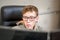 The teenager works at the computer. A young guy with glasses sits in an armchair and looks at several monitors. Red-haired