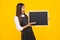 Teenager younf school girl holding school empty blackboard isolated on yellow background. Portrait of a teen female