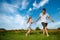 Teenagers: brother and sister are running and enjoying weather, in meadow against cloudy sky