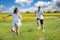 Teenagers: brother and sister are running and enjoying weather, in meadow against cloudy sky