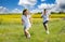 Teenagers: brother and sister are running and enjoying weather, in meadow against cloudy sky