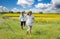 Teenagers: brother and sister are running and enjoying weather, in meadow against cloudy sky