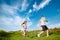 Teenagers: brother and sister are running and enjoying weather, in meadow against cloudy sky