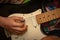 Teenagers hands playing an electric base guitar with a pick