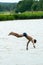 Teenagers jump into the water and swim in the lake on a hot summer day. Active recreation on an open pond. Children jump into the