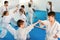 Teenagers practicing new karate moves in pairs in class
