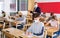 Teenagers in protective masks studying in classroom with teacher