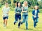 Teenagers running through green lawn in summer in park