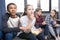 Teenagers sitting on sofa and eating popcorn from bowl indoors