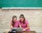 Teenagers young schoolgirls with laptop on blackboard at school. Portrait of a teens female students.