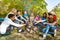 Teens grilling sausages on campsite sitting close