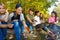 Teens grilling sausages sitting near yellow tent