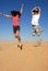 Teens joyfully leaping in desert dunes under a blue sky, reveling in playful moments and boundless enjoyment