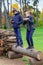 Teens relaxing outdoor in autumn city park, happy people together, boy and girl, they standing on a log, playing, talking and
