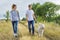 Teens walking with white dog in meadow on sunny day