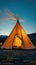 Teepee structure set in a vast field, surrounded by distant mountains under a clear sky