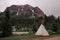 A teepee wigwam tent is standing alone in the forest. Active recreation in the mountains