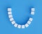 Teeth made of sugar cubes on blue background, one tooth missing. Sweet tooth dental health care concept