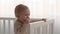 Teething In Babies. Adorable Infant Kid Standing In Bed And Chewing Fingers