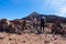 Teide - Couple holding hands on volcanic desert terrain hiking trail leading to summit volcano Pico del Teide, Tenerife, Spain.
