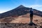 Teide - Hiking man with backpack standing on the summit Pico Viejo with scenic view on the peak of volcano Pico del Teide