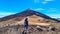 Teide - Hiking woman with backpack standing on the summit Pico Viejo with scenic view on the peak of volcano Pico del Teide