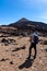 Teide - Man with backpack on volcanic desert terrain hiking trail leading to summit volcano Pico del Teide, Tenerife, Spain.