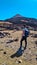 Teide - Man with backpack on volcanic desert terrain hiking trail leading to summit volcano Pico del Teide, Tenerife, Spain.