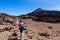 Teide - Woman with backpack on volcanic desert terrain hiking trail leading to summit volcano Pico del Teide, Tenerife, Spain.