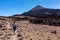 Teide - Woman with backpack on volcanic desert terrain hiking trail leading to summit volcano Pico del Teide, Tenerife, Spain.