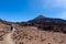Teide - Woman with backpack on volcanic desert terrain hiking trail leading to summit volcano Pico del Teide, Tenerife, Spain.