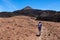 Teide - Woman with backpack on volcanic desert terrain hiking trail leading to summit volcano Pico del Teide, Tenerife, Spain.