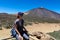 Teide - Woman on rock with view on La Canada de los Guancheros dry desert plain and volcano Pico del Teide