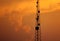 The telacommunication pole with sunset sky background. the silhouette electric workers working on high ground with safety uniform