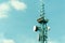 Telecommunication antennas outdoor on the tall metal pole construction with digital clock display and blue sky background close up