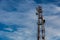 Telecommunication pole with several kinds of antennas in blue sky and clouds in sunny bright day with copy space