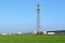 Telecommunication tower in the field in front of the industrial area