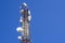 Telecommunications tower with cellular antenna on blue sky background. Look up