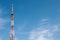 A telecommunications tower made of metal amid a blue sky with clouds.