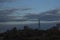 The telecommunications tower stands on a hill under a cloudy sky. Autumn landscape.