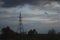 A telecommunications tower stands in the middle of a field under a cloudy sky. Autumn landscape.