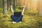 Telecommuting - man with laptop laying in the moss in the forest with hands raised